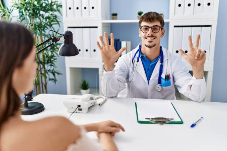 Photo for Young doctor with client at medical clinic showing and pointing up with fingers number eight while smiling confident and happy. - Royalty Free Image