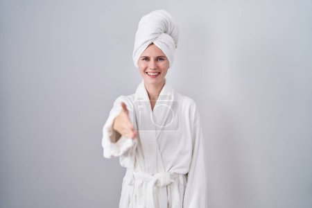 Photo for Blonde caucasian woman wearing bathrobe smiling friendly offering handshake as greeting and welcoming. successful business. - Royalty Free Image