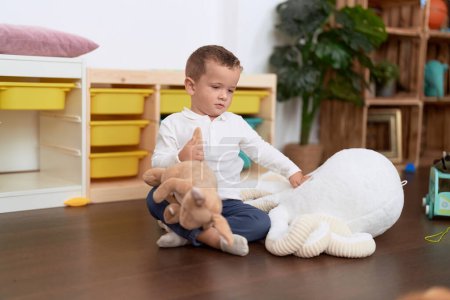 Foto de Adorable niño jugando con muñecas sentadas en el suelo en casa - Imagen libre de derechos