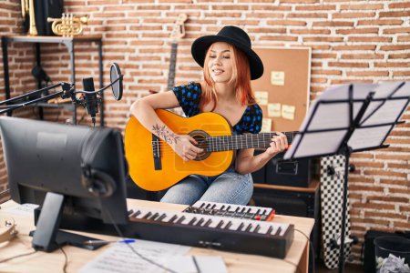 Foto de Joven mujer caucásica músico tocando guitarra clásica en el estudio de música - Imagen libre de derechos