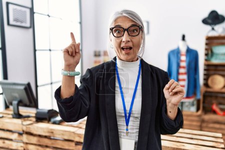 Photo for Middle age grey-haired woman working as manager at retail boutique pointing finger up with successful idea. exited and happy. number one. - Royalty Free Image