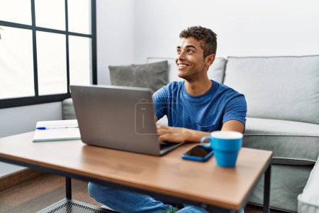 Photo for Young hispanic man using laptop sitting on the floor at home - Royalty Free Image