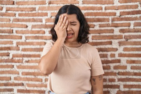 Photo for Young hispanic woman standing over bricks wall yawning tired covering half face, eye and mouth with hand. face hurts in pain. - Royalty Free Image