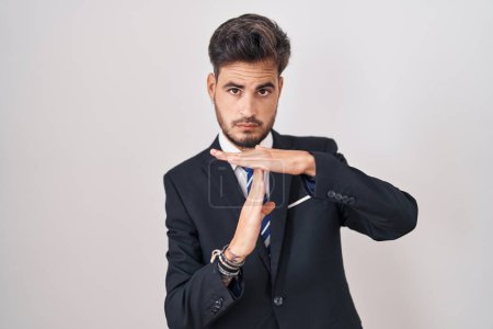 Photo for Young hispanic man with tattoos wearing business suit and tie doing time out gesture with hands, frustrated and serious face - Royalty Free Image