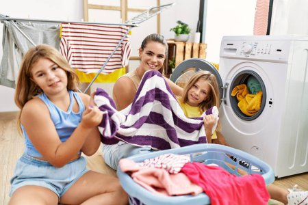 Photo for Mother and daughters washing clothes smelling towel at laundry room - Royalty Free Image