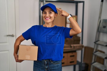 Photo for Middle age brunette woman working wearing delivery uniform and cap smiling pointing to head with one finger, great idea or thought, good memory - Royalty Free Image