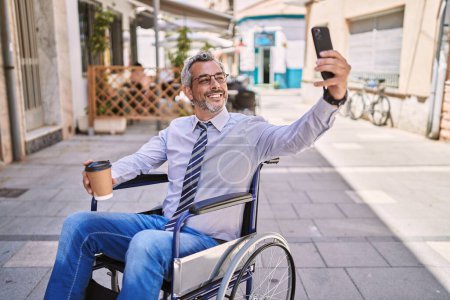 Photo for Middle age hispanic man sitting on wheelchair makes selfie by the smartphone at street - Royalty Free Image