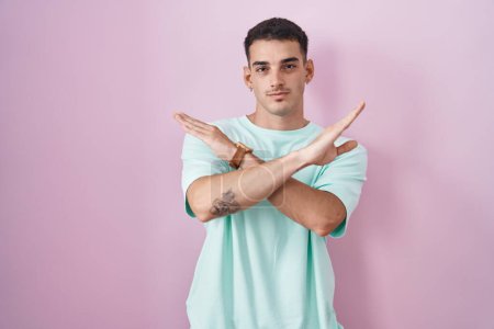 Téléchargez les photos : Bel homme hispanique debout sur fond rose expression de rejet croisant les bras faisant signe négatif, visage en colère - en image libre de droit