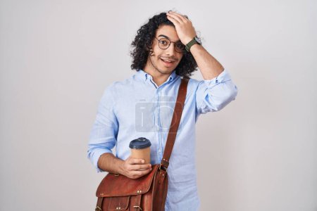 Téléchargez les photos : Homme hispanique avec les cheveux bouclés boire une tasse de café à emporter surpris avec la main sur la tête pour erreur, rappelez-vous erreur. oublié, mauvais concept de mémoire. - en image libre de droit