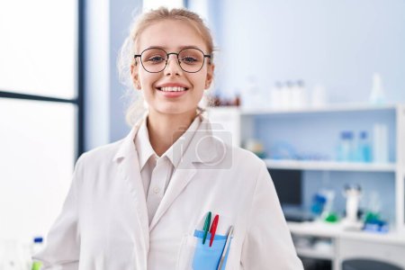 Photo for Young blonde woman scientist smiling confident standing at laboratory - Royalty Free Image