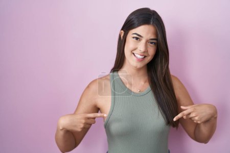 Photo for Hispanic woman standing over pink background looking confident with smile on face, pointing oneself with fingers proud and happy. - Royalty Free Image