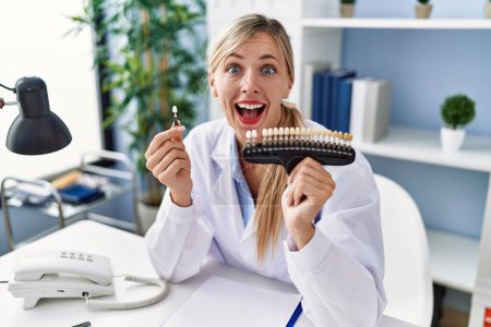 Téléchargez les photos : Beautiful dentist woman comparing teeth whitening celebrating crazy and amazed for success with open eyes screaming excited. - en image libre de droit