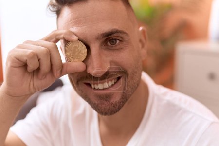 Téléchargez les photos : Young hispanic man holding litecoin crypto currency over eye at home - en image libre de droit