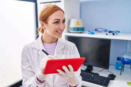 Photo for Young caucasian woman scientist smiling confident using touchpad at laboratory - Royalty Free Image
