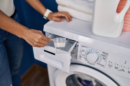 Téléchargez les photos : Young blonde woman pouring detergent on washing machine at laundry room - en image libre de droit