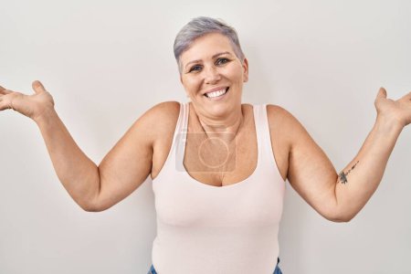 Photo for Middle age caucasian woman standing over white background clueless and confused expression with arms and hands raised. doubt concept. - Royalty Free Image