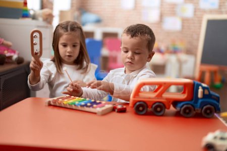 Foto de Adorable chica y niño jugando xilófono sentado en la mesa en el jardín de infantes - Imagen libre de derechos