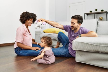 Foto de Couple and daughter smiling confident playing with toys sitting on the floor at home - Imagen libre de derechos