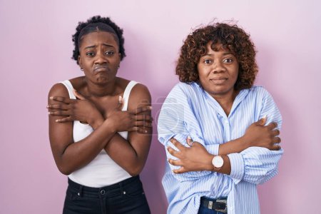 Photo for Two african women standing over pink background shaking and freezing for winter cold with sad and shock expression on face - Royalty Free Image