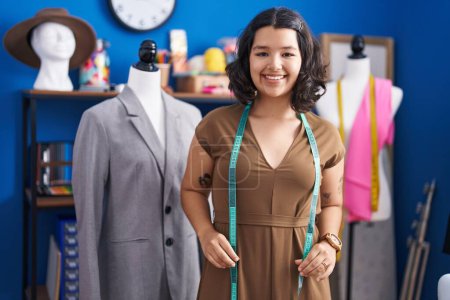 Téléchargez les photos : Jeune femme tailleur souriant confiant debout au studio de couture - en image libre de droit