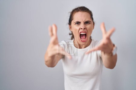 Photo for Beautiful brunette woman standing over isolated background angry and mad raising fists frustrated and furious while shouting with anger. rage and aggressive concept. - Royalty Free Image