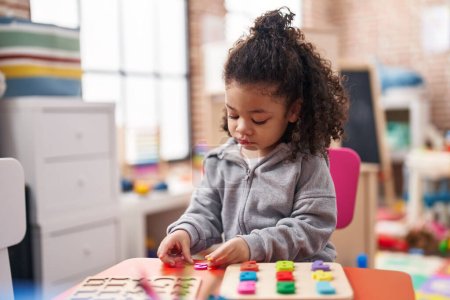 Téléchargez les photos : African american toddler jouer avec des mathématiques jeu de puzzle debout à la maternelle - en image libre de droit