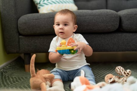 Foto de Adorable niño jugando con juguetes sentados en el suelo en casa - Imagen libre de derechos