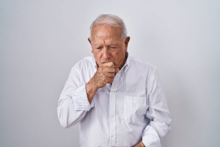 Téléchargez les photos : Homme âgé aux cheveux gris debout sur un fond isolé se sentant mal à l'aise et toussant comme symptôme de rhume ou de bronchite. concept de soins de santé. - en image libre de droit