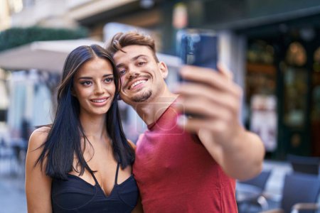 Foto de Hombre y mujer pareja sonriendo confiado hacer selfie por teléfono inteligente en la terraza de la cafetería - Imagen libre de derechos