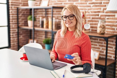 Photo for Young blonde woman smiling confident using laptop and credit card at home - Royalty Free Image