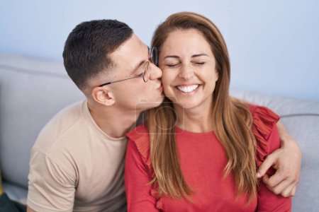 Téléchargez les photos : Homme et femme mère et fils s'embrassant et s'embrassant assis sur le canapé à la maison - en image libre de droit