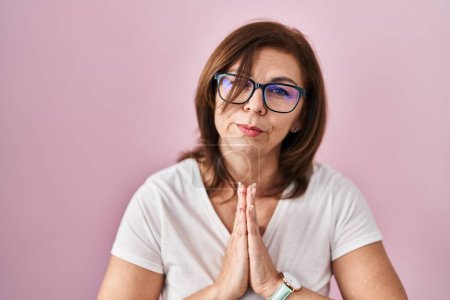 Photo for Middle age hispanic woman standing over pink background begging and praying with hands together with hope expression on face very emotional and worried. begging. - Royalty Free Image