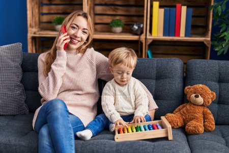 Photo for Mother and son talking on the smartphone and playing with abacus at home - Royalty Free Image