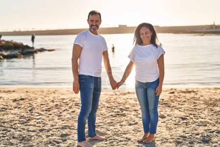 Photo for Middle age man and woman couple standing with hands together at seaside - Royalty Free Image