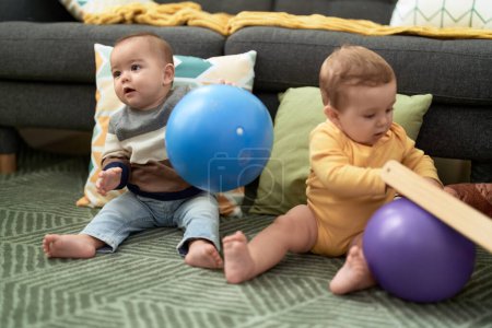 Foto de Dos niños jugando con pelotas sentados en el suelo en casa - Imagen libre de derechos
