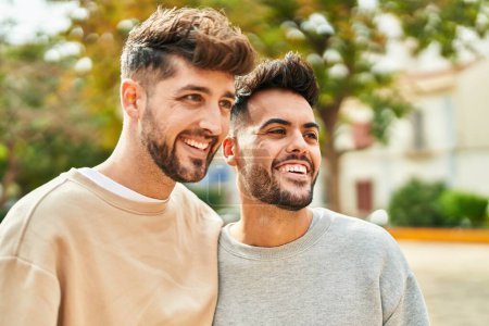 Téléchargez les photos : Jeune couple souriant confiant se serrant dans ses bras au parc - en image libre de droit