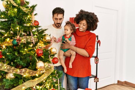 Téléchargez les photos : Couple et fille souriant confiant décoration arbre de Noël à la maison - en image libre de droit