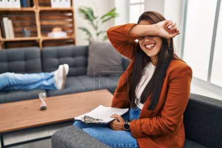 Photo for Young hispanic woman working as psychology counselor smiling cheerful playing peek a boo with hands showing face. surprised and exited - Royalty Free Image