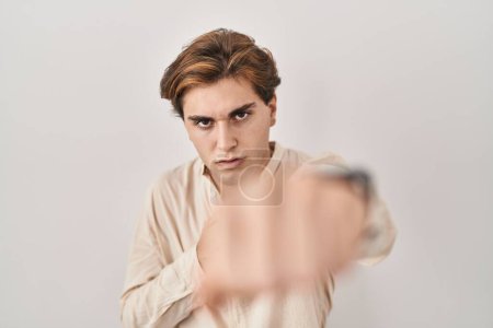 Photo for Young man standing over isolated background punching fist to fight, aggressive and angry attack, threat and violence - Royalty Free Image