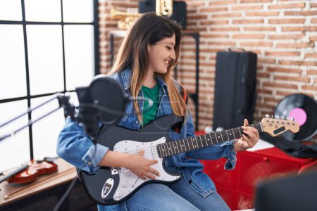 Téléchargez les photos : Jeune musicienne hispanique chantant une chanson jouant de la guitare électrique au studio de musique - en image libre de droit