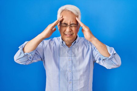 Foto de Hombre mayor hispano usando gafas con la mano en la cabeza, dolor de cabeza porque el estrés. padecer migraña. - Imagen libre de derechos