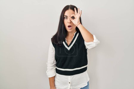 Photo for Young hispanic woman standing over isolated background doing ok gesture shocked with surprised face, eye looking through fingers. unbelieving expression. - Royalty Free Image