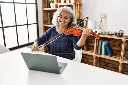 Foto de Mujer de pelo gris de mediana edad tocando el concierto de violín en línea en el estudio de radio. - Imagen libre de derechos
