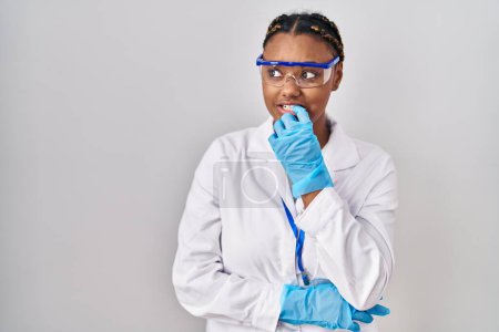 Photo for African american woman with braids wearing scientist robe looking stressed and nervous with hands on mouth biting nails. anxiety problem. - Royalty Free Image