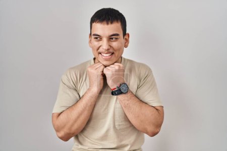 Photo for Young arab man wearing casual t shirt laughing nervous and excited with hands on chin looking to the side - Royalty Free Image