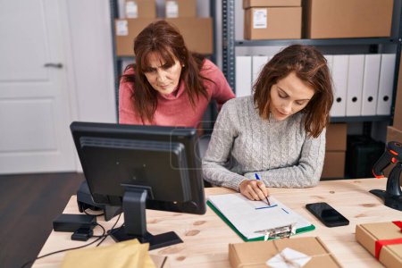 Téléchargez les photos : Two women ecommerce business workers writing on document at office - en image libre de droit