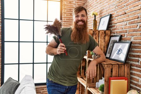 Photo for Young redhead man smiling confident cleaning dust at home - Royalty Free Image