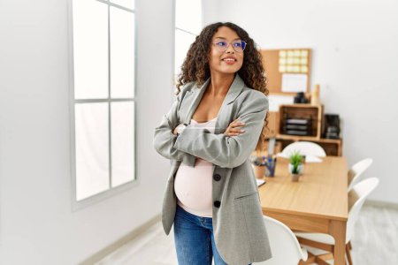 Photo for Young latin woman pregnant smiling confident standing with arms crossed gesture at office - Royalty Free Image