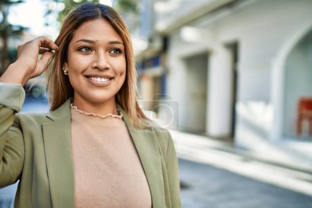 Téléchargez les photos : Jeune femme latine souriant confiant à la rue - en image libre de droit