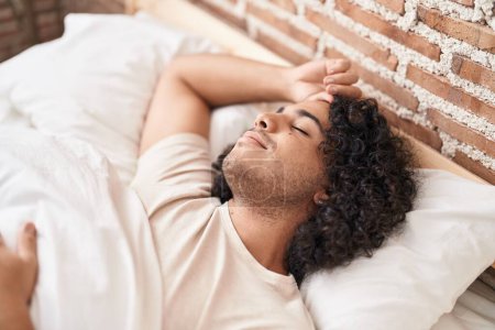Téléchargez les photos : Jeune homme latin couché sur le lit dormant dans la chambre - en image libre de droit
